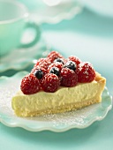 A slice of cheese cake topped with raspberries and blueberries