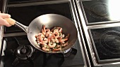 Sautéing prawns with garlic, chilli and herbs in a wok