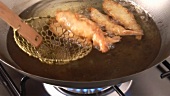 Taking deep-fried prawns out of fat with a skimmer