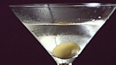 Martini mit einer Olive garnieren