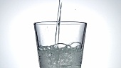 Ein Glas Mineralwasser einschenken