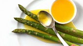 Spooning melted butter over asparagus
