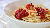 Spaghetti mit Tomatensauce um die Gabel wickeln