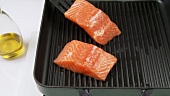 Cutting salmon fillet into pieces and frying it in a grill frying pan