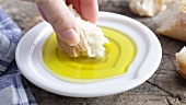 Dipping a piece of white bread in olive oil