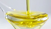 Olivenöl über einen Salatlöffel gießen