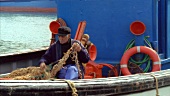 Fischer sitzt im Boot mit seinem Fischernetz
