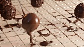 Placing chocolate-coated chocolate truffle on draining rack