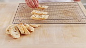 Ciabatta slices being placed on an oven rack