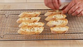 Garlic being rubbed onto slices of toasted bread