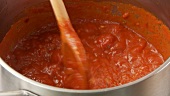 Simmering tomato sauce being stirred