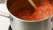 Simmering tomato sauce being stirred
