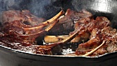Lamb chops being fried in a pan