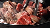 Beef being turned over in a hot pan