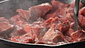 Beef being turned over in a pan
