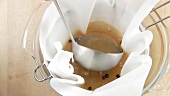 Broth being sieved through a sieve lined with kitchen paper