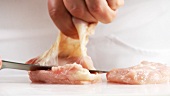 Chicken breasts being skinned and the fat and sinews cut away (German Voice Over)