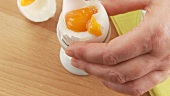 A breakfast egg being cut with a knife and salted