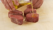 Beef fillet slices being drizzled with olive oil