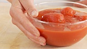 A hand taking a dish of tinned tomatoes