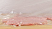 Clingfilm being removed from a tenderised slice of veal