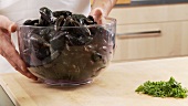 A bowl of fresh mussels being placed on a work surface