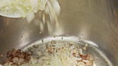 Onions being added to bacon and fried
