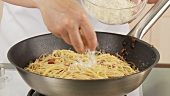 Eigelb-Sahne-Mischung über die Spaghetti gießen, verrühren und mit Parmesan bestreuen