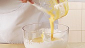 Egg yolk cream being added to beaten egg white