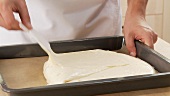 Sponge cake dough being spread in a baking tray