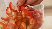 Strawberry pieces being put into a bowl