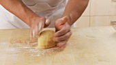 A ball of shortcrust pastry being shaped into a ball