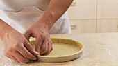Dough being pressed firmly in a tart dish