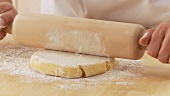 Shortcrust pastry being removed from clingfilm and rolled out