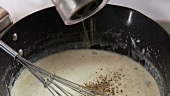 Gorgonzola sauce being seasoned with pepper