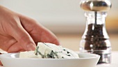 A hand taking gorgonzola and a pepper mill