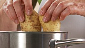 Potatoes in their skins being put in a pot