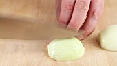 An onion being halved and diced