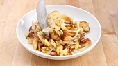 Fried potatoes with onions being arranged on a plate