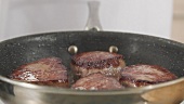 Beef steaks being fried in a pan