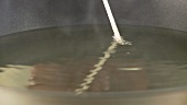 The temperature of frying fat being checked (wooden stick test)