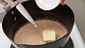 A piece of butter being stirred into gravy