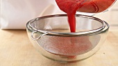 Raspberry sauce being sieved