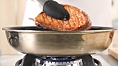 Duck breast being turned in a pan