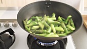 Green asparagus being cooked in a pan