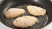 Breaded chicken breasts being fried
