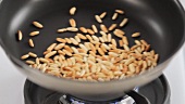Pine nuts being roasted in a pan