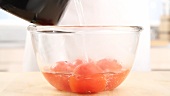 Boiling water being poured over tomatoes