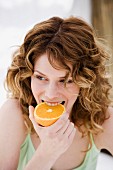 Junge Frau beisst in eine halbe Orange