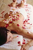 Young woman covered with rose petals